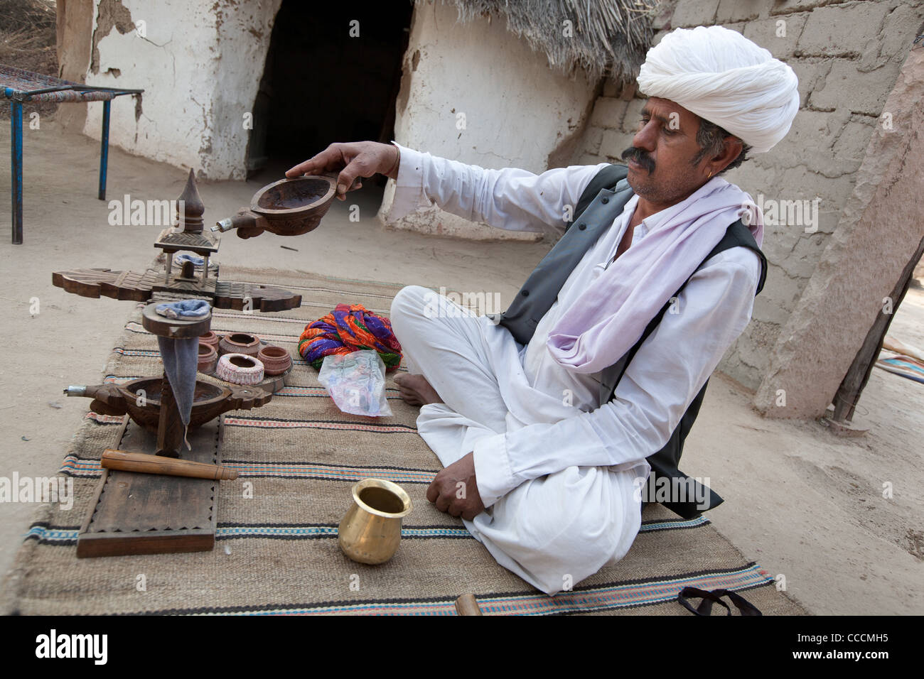 Anziano maschile in un villaggio di Bishnoi esegue una cerimonia di oppio, a Rajasthan, India. Foto Stock