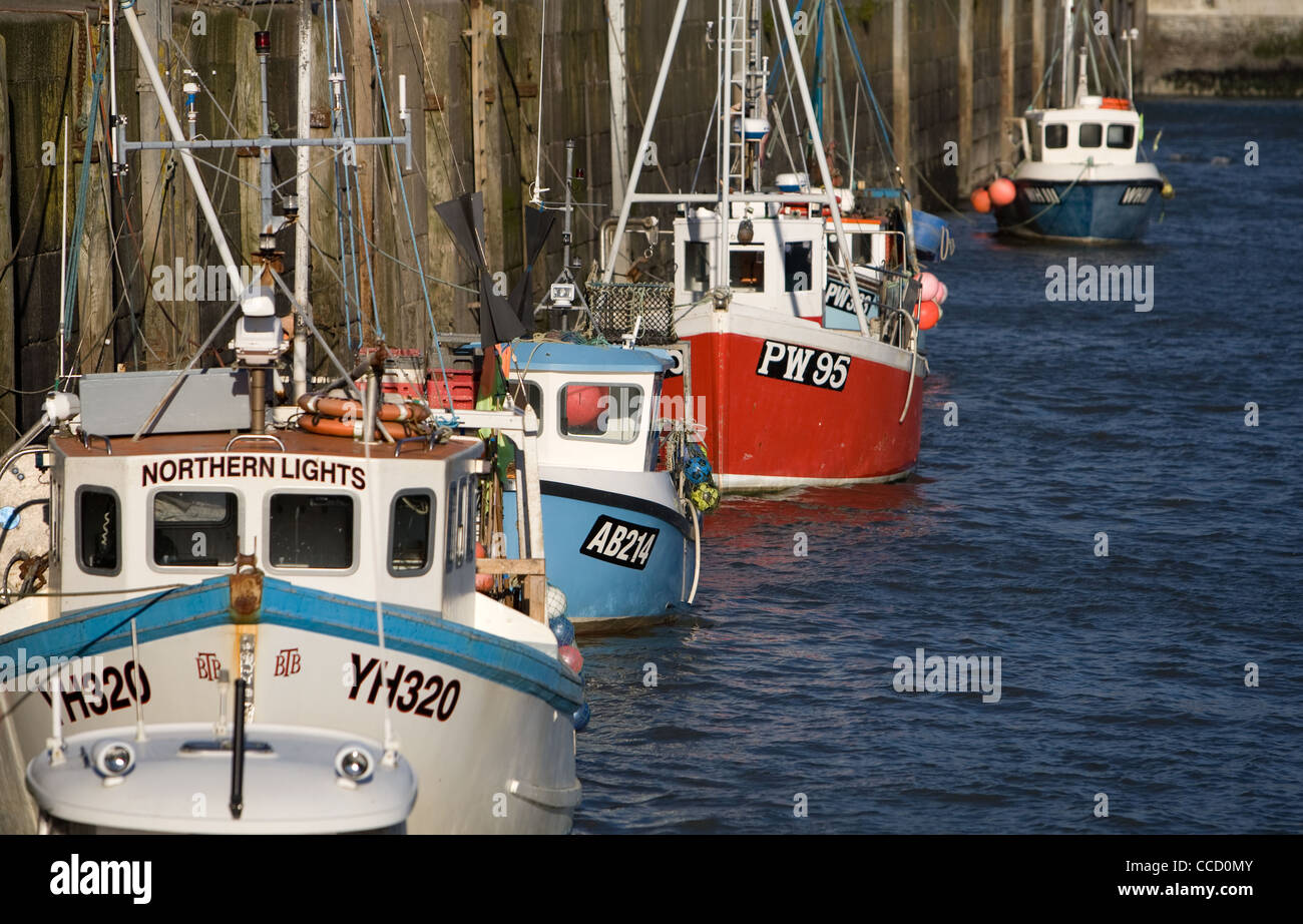 Ormeggiate barche da pesca schierate contro la parete del porto a Padstow, Cornwall. Foto Stock