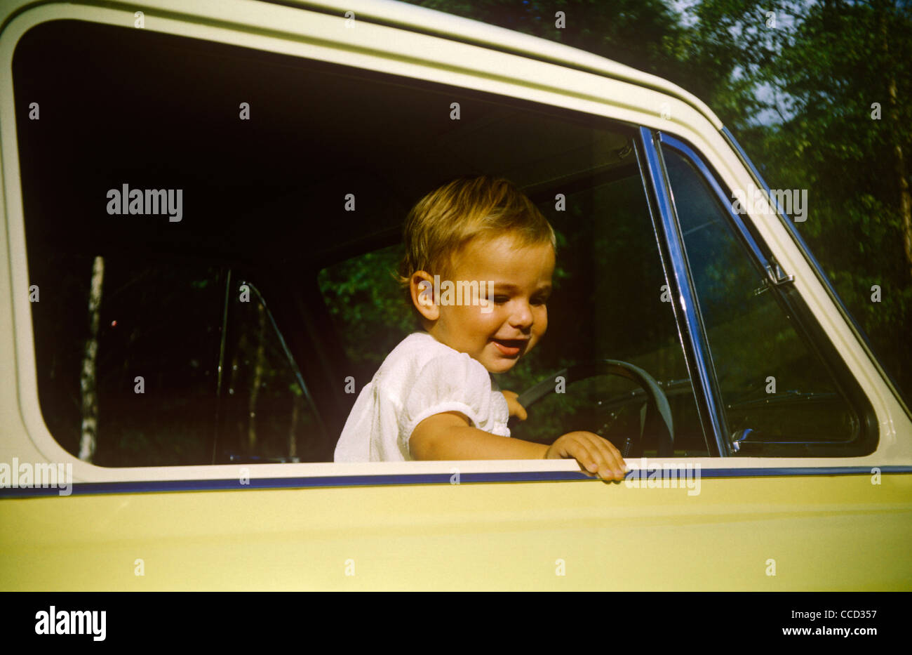 Un ragazzo si alza di suo padre Anglia auto in un giorno di estate fuori nei primi anni sessanta. Foto Stock