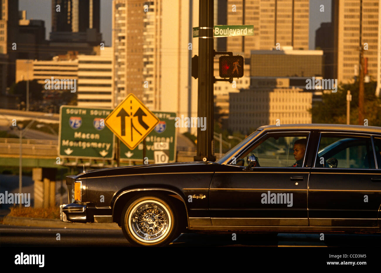 Un driver nel suo gas-guzzling auto e in background, lo skyline del centro di Atlanta. Foto Stock