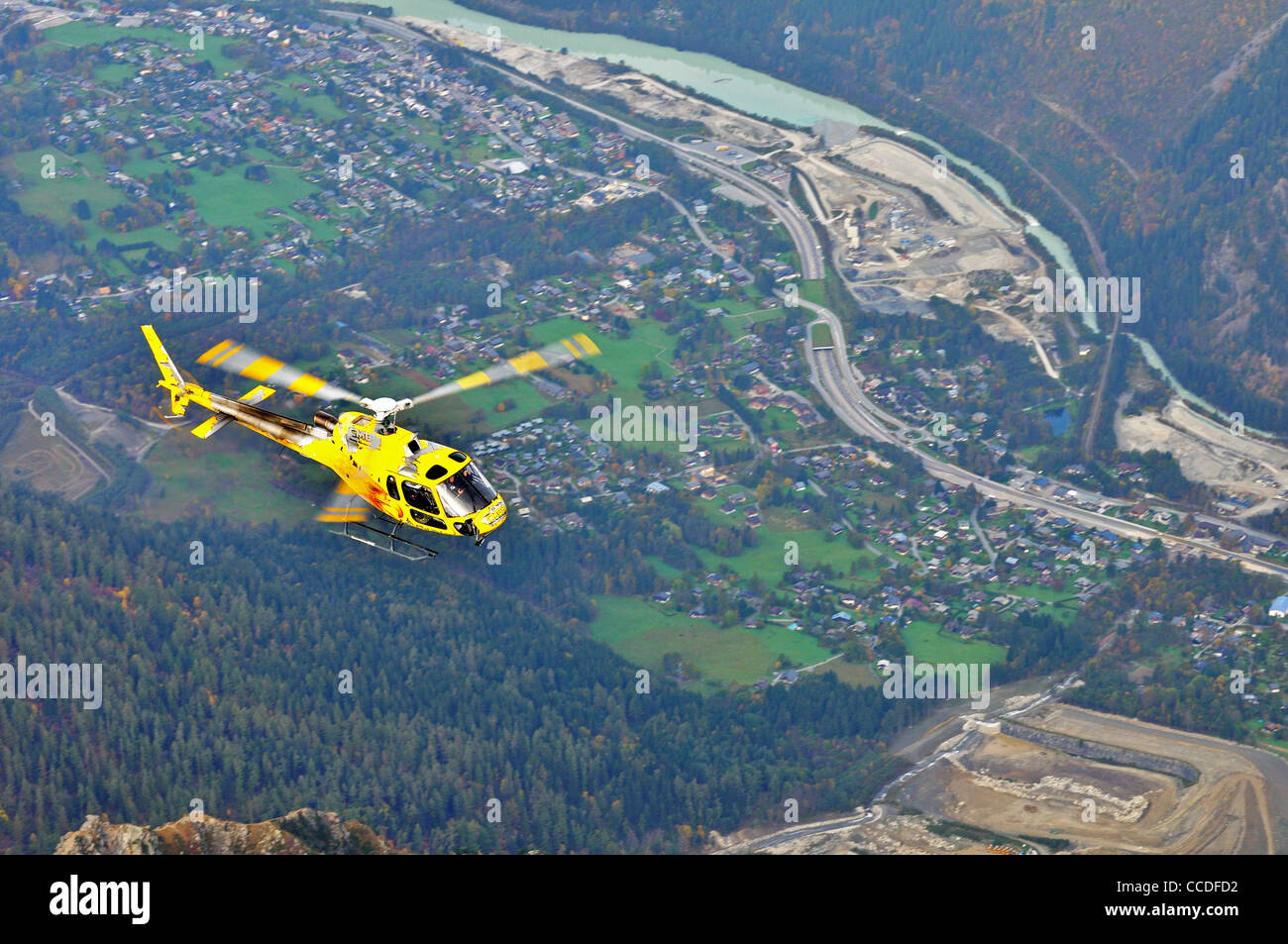 Elicottero giallo con turisti di ritorno dalla gita turistica volando sopra la città di Chamonix, sulle Alpi francesi, Francia Foto Stock