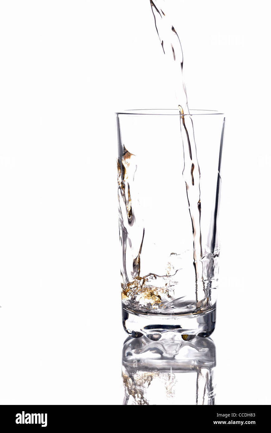 Versare nella più grande bicchiere vuoto, sfondo bianco. Foto Stock