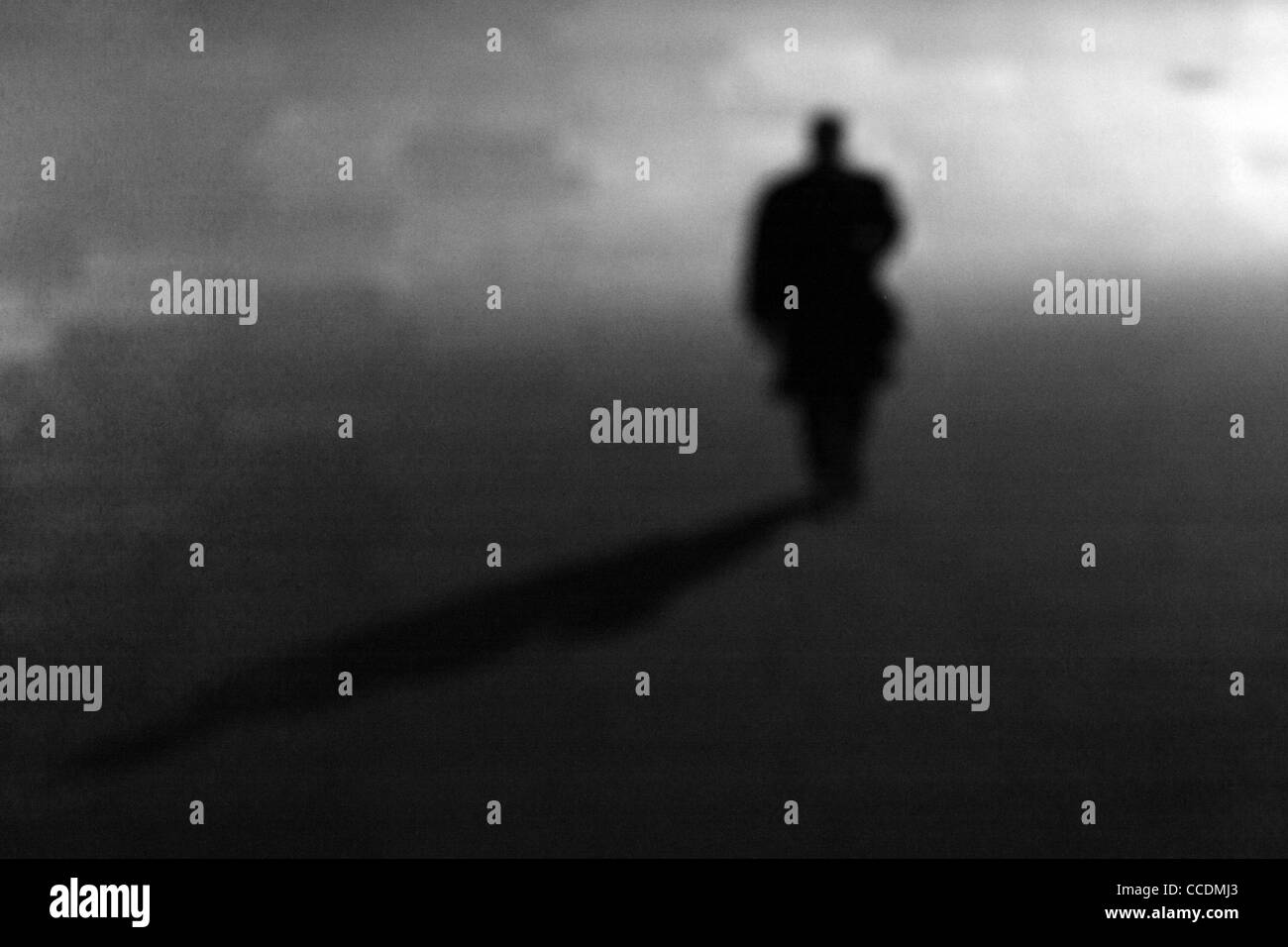 Al di fuori della messa a fuoco la silhouette di un uomo a camminare da soli di notte in un luogo deserto Foto Stock