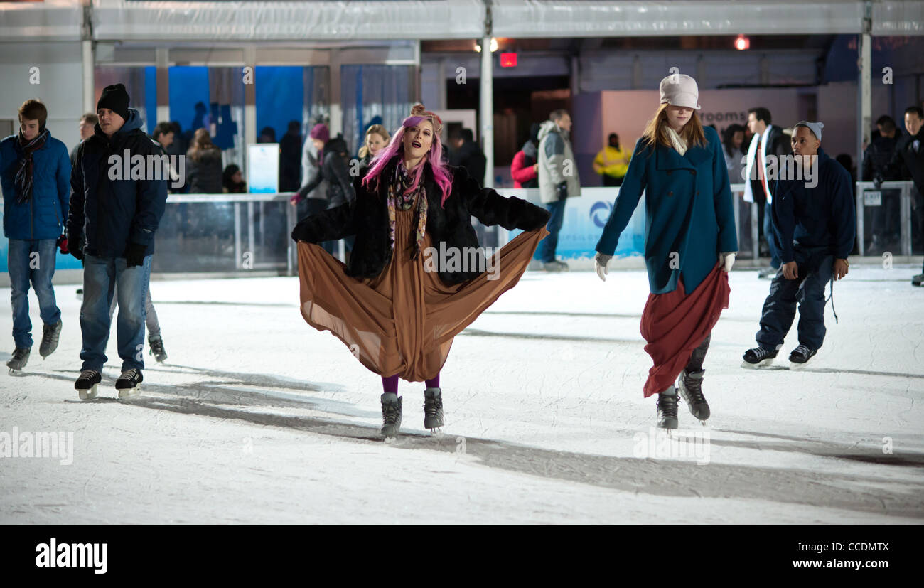 I pattinatori vestito in abiti formali manovrare il pranzo stagno al Bryant Park pista di pattinaggio su ghiaccio in New York Foto Stock