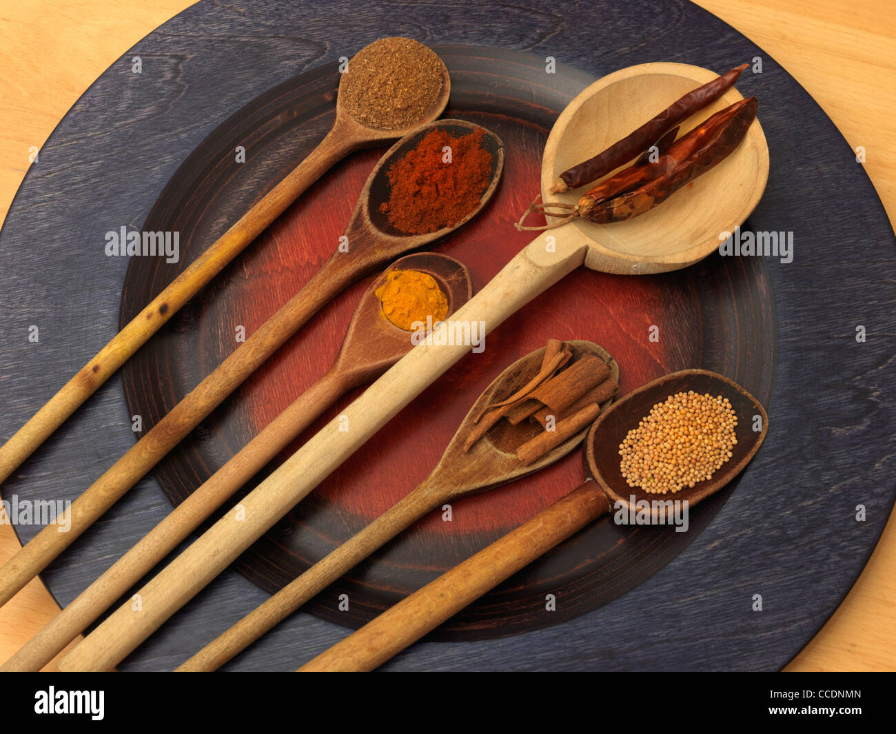Raccolta di spezie su cucchiai di legno su una piastra Caram Masala, affumicati la paprica, la curcuma, il peperoncino, cannella e semi di senape Foto Stock