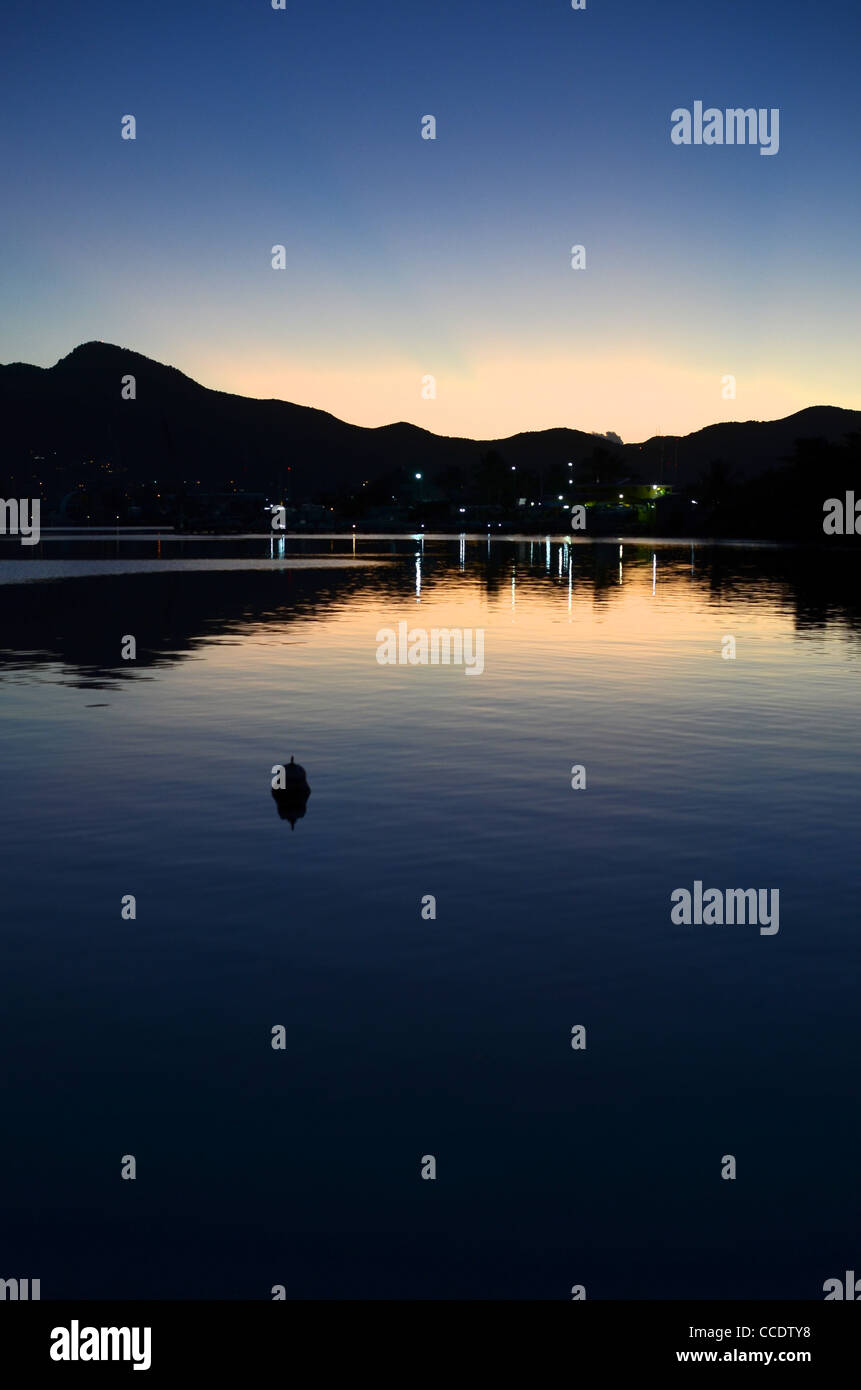 Alba di mattina presto dietro le montagne che gettano una luce ambientale sulla laguna. Orizzontale verticale. Foto Stock