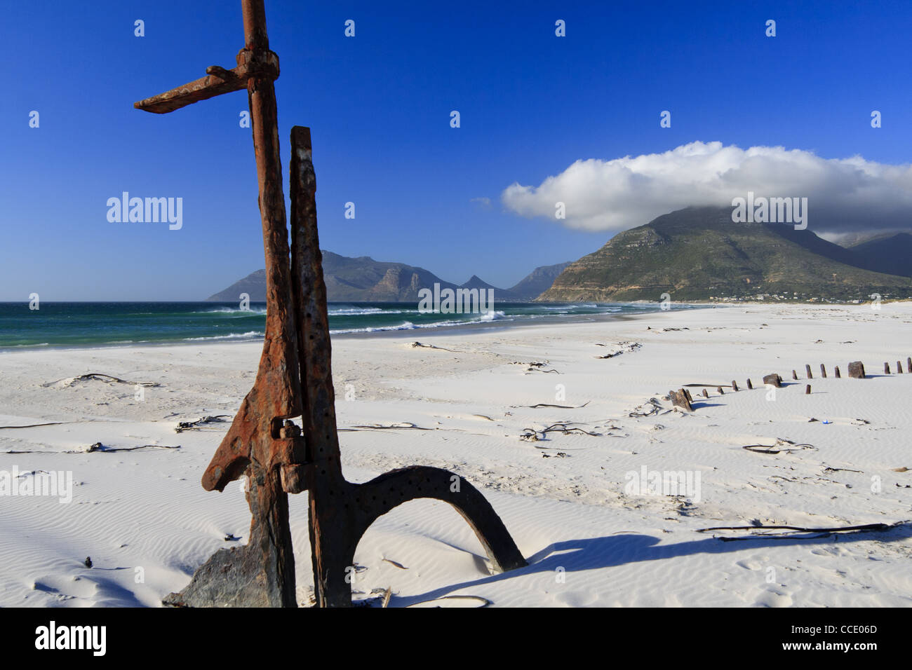 Naufragio con timone sulla spiaggia con uno sfondo montano Foto Stock