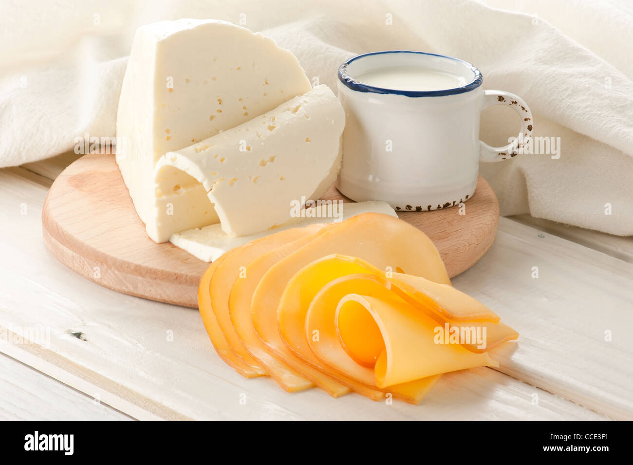 La prima colazione con il latte e il formaggio su un vecchio tavolo di legno con tovaglie di lino Foto Stock