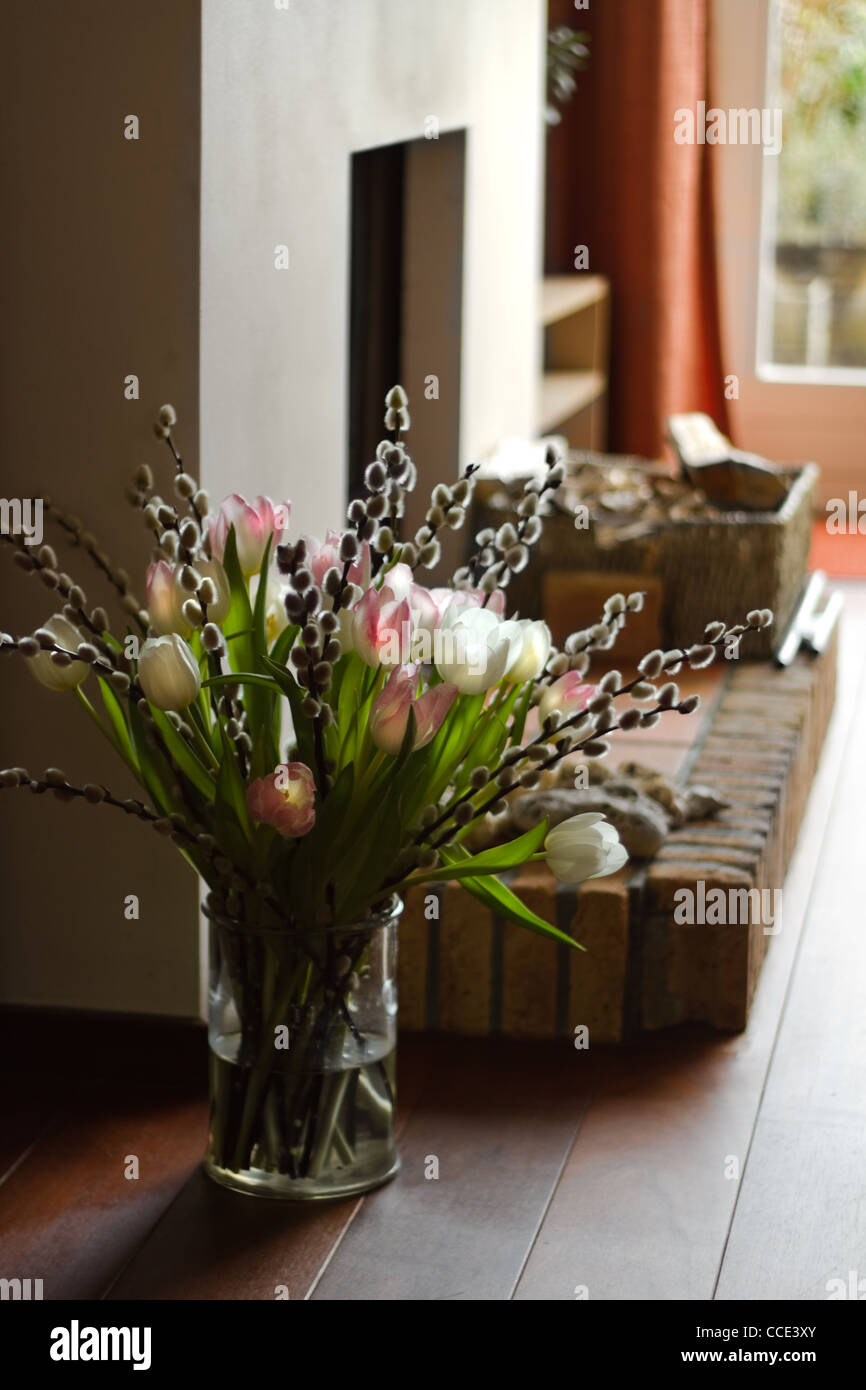 Parte di interno con camino e bouquet di springflowers - verticale Foto Stock