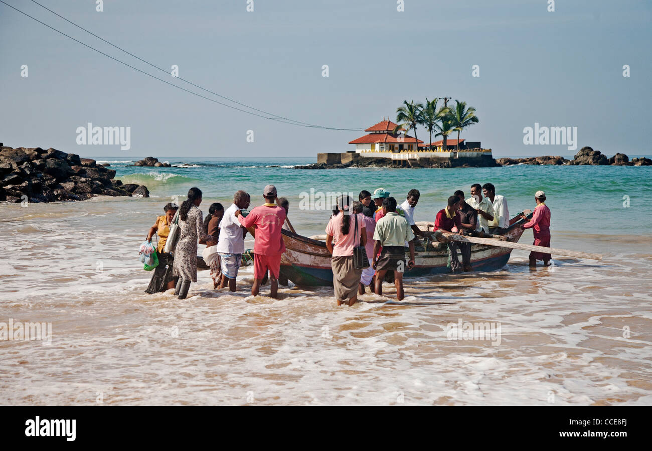 Persone di salire a bordo di una barca per prendere il loro tempio isola offshore, Hikkaduwa, Sri Lanka Foto Stock