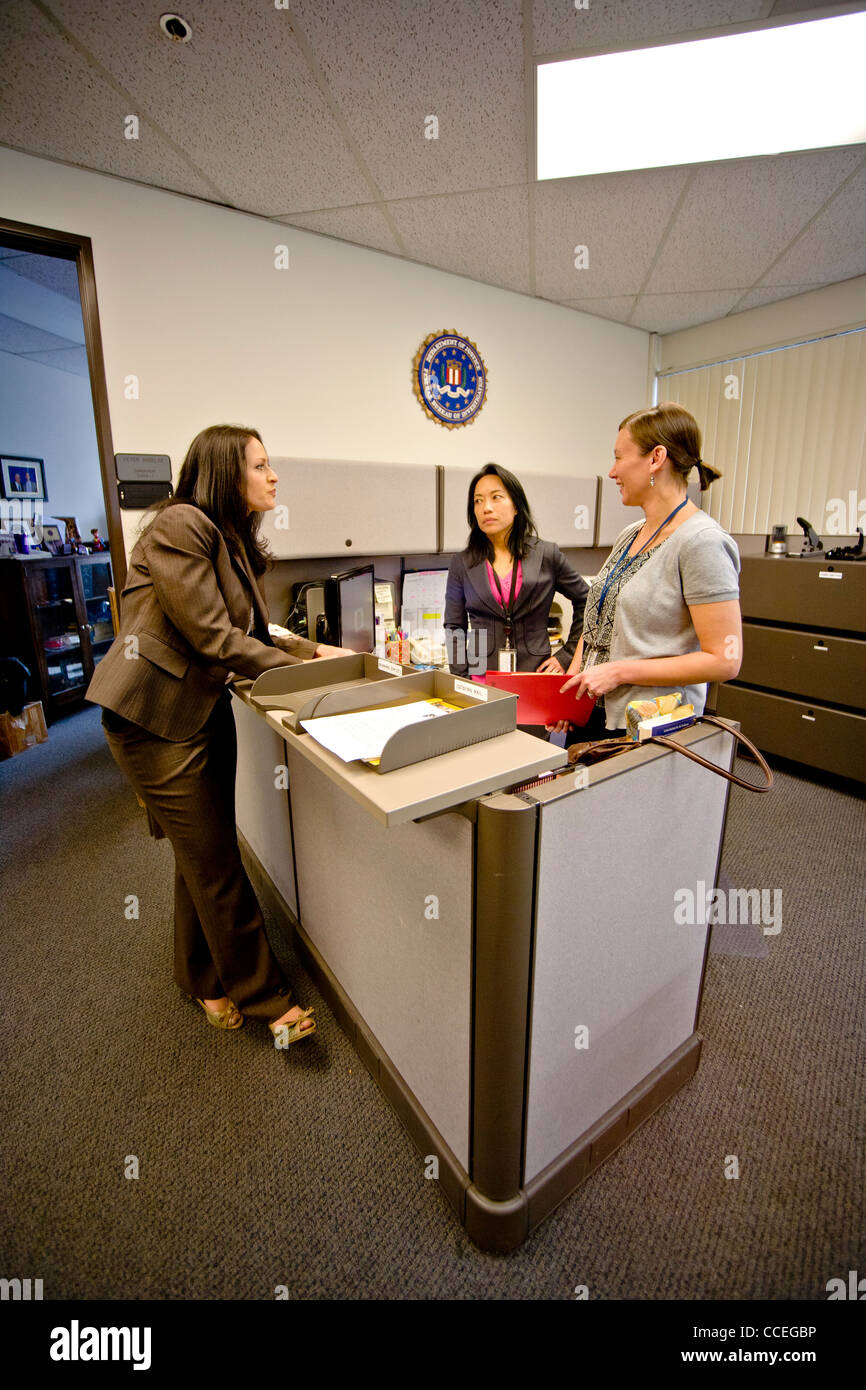 Femmina di tre agenti FBI discutere un caso in Santa Ana CA, office. Nota Filipino-American in centro e FBI logo sul muro. Rilasciato Foto Stock