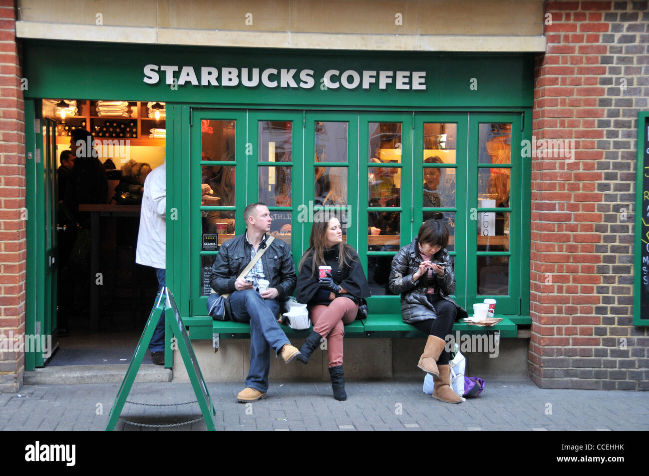 Starbucks Coffee Neal Street Covent Garden di Londra a bere caffè rilassante pausa caffè texting uno stile di vita urbano Foto Stock