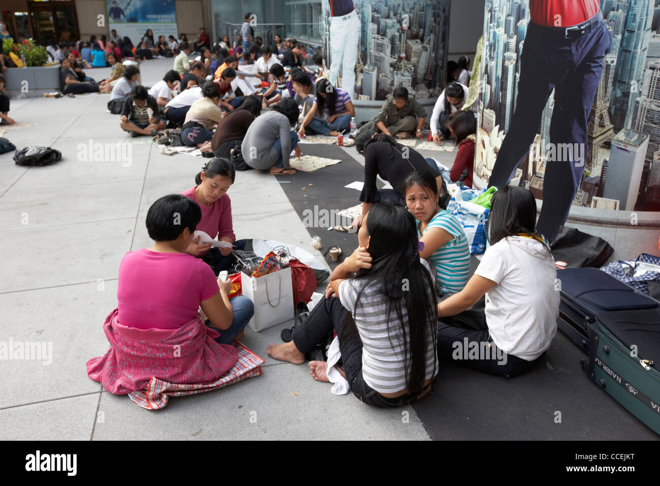 Filippina e cinese personale domestico sulla loro giornata seduti in gruppi sul marciapiede esterno edificio hsbc hong kong RAS di Hong Kong Foto Stock
