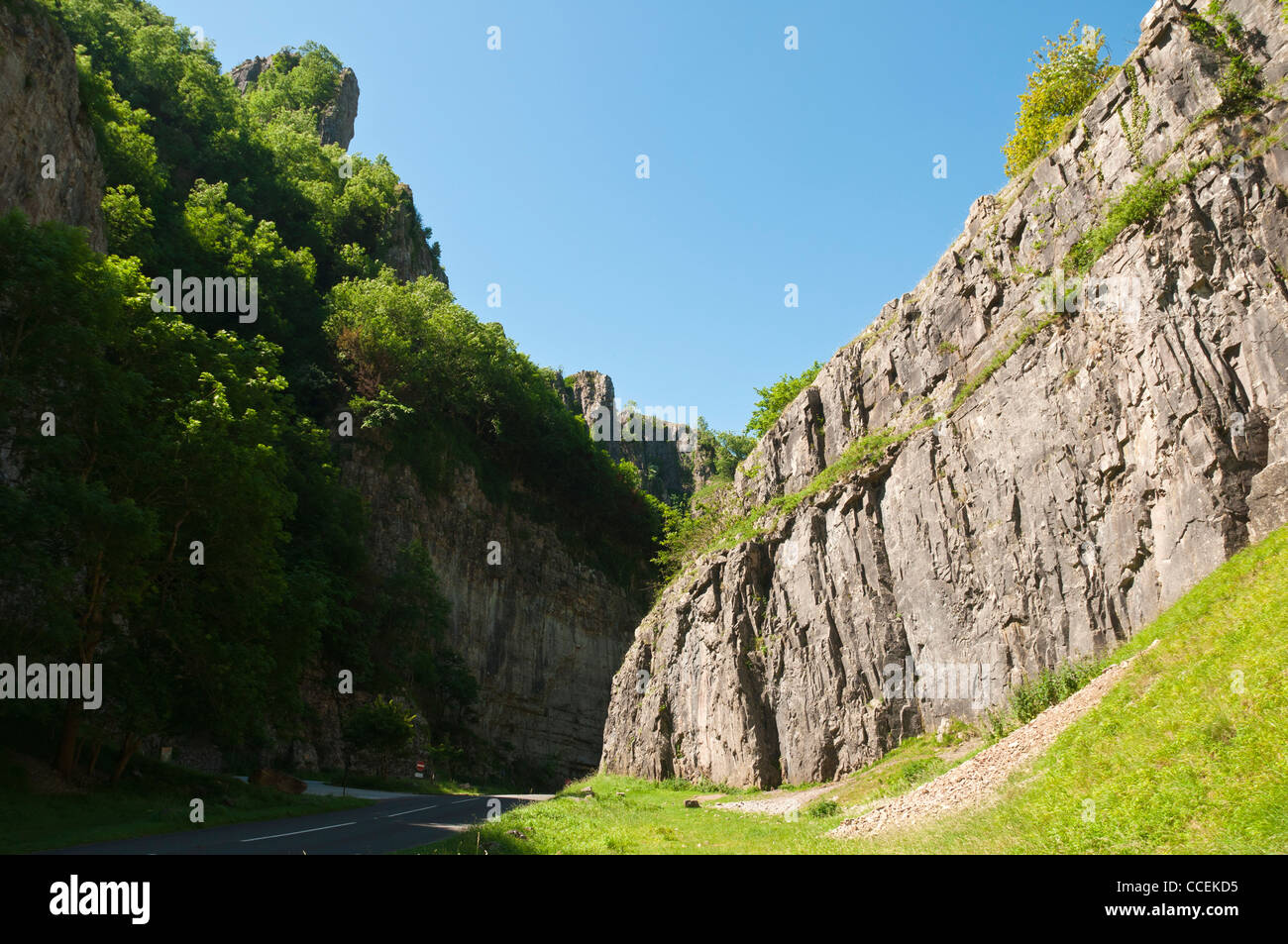 Una luminosa giornata estiva nel mondo famoso Cheddar Gorge nel Somerset in vista della strada che passa un grande promontorio roccioso Foto Stock