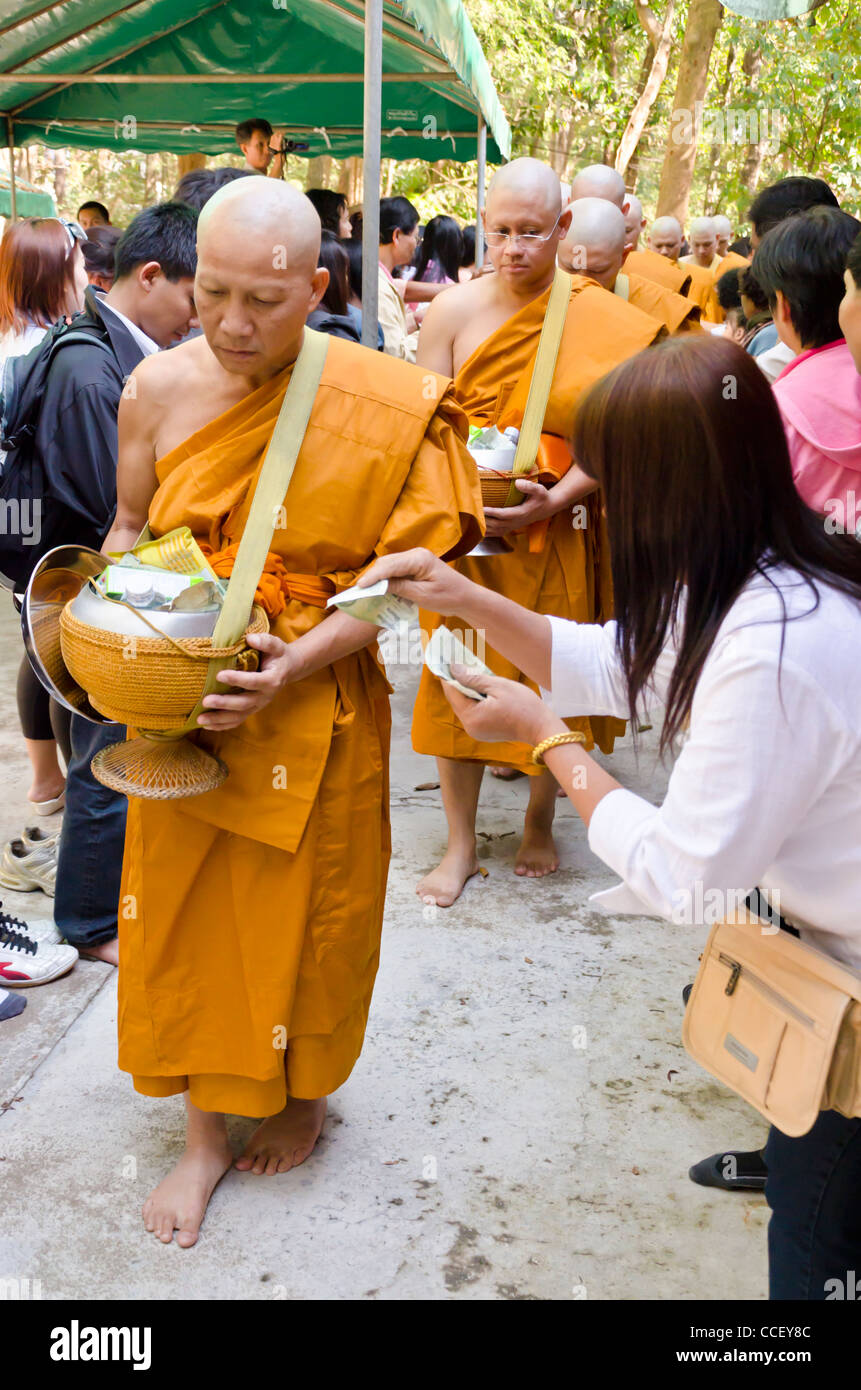 Nuovi ordinati i monaci buddisti con teste rasate & indossando arancione vesti a piedi da persone mettere doni in ciotole stanno portando Foto Stock