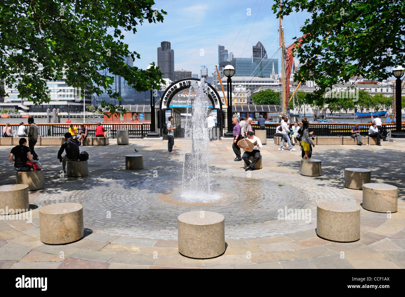 Fontana & area pavimentata fuori dall'ingresso al Ponte di Londra City pier accanto al Fiume Tamigi con skyline della città al di là di Southwark London REGNO UNITO Foto Stock