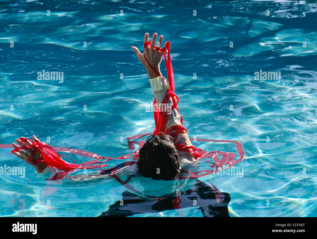 Uomo che annega nel nastro rosso Foto Stock