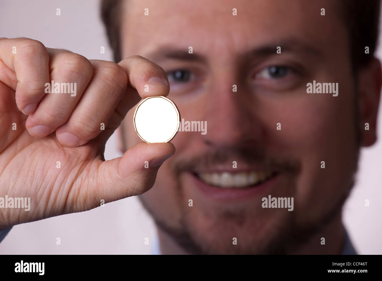 Uomo sorridente in possesso di una moneta in oro Foto Stock