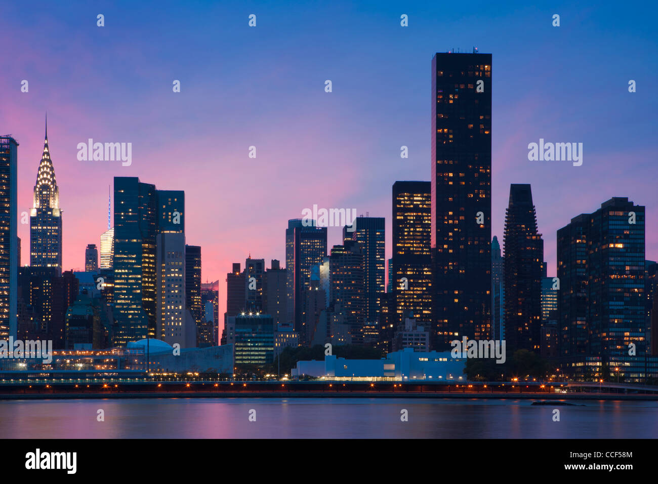 Rosa e azzurro cielo dietro il Manhattan Midtown Skyline da East River Foto Stock