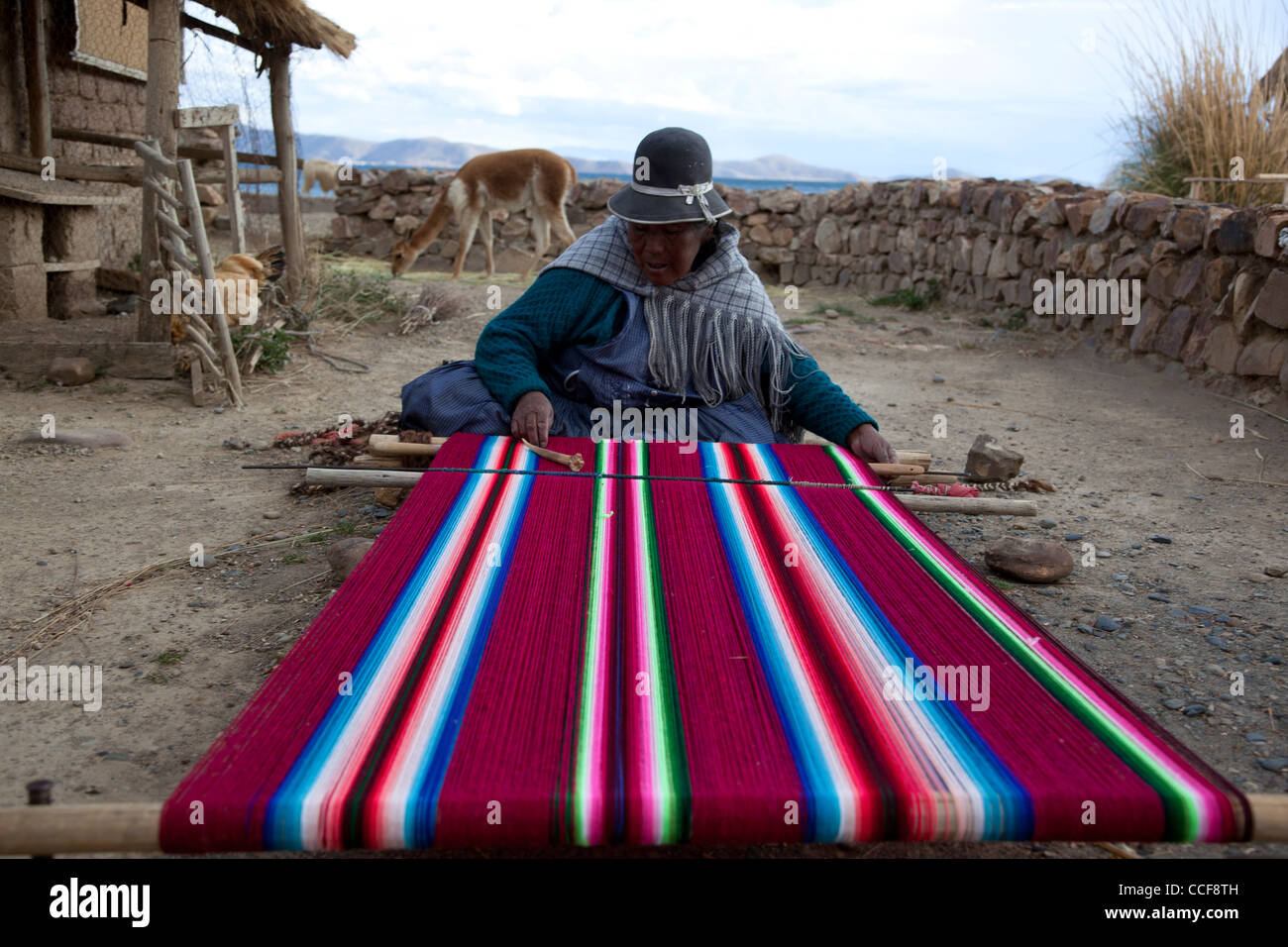 Una donna Aymara tesse su un tradizionale telaio a mano in Huatajata sul Boliviano della riva del lago Titicaca. Foto Stock