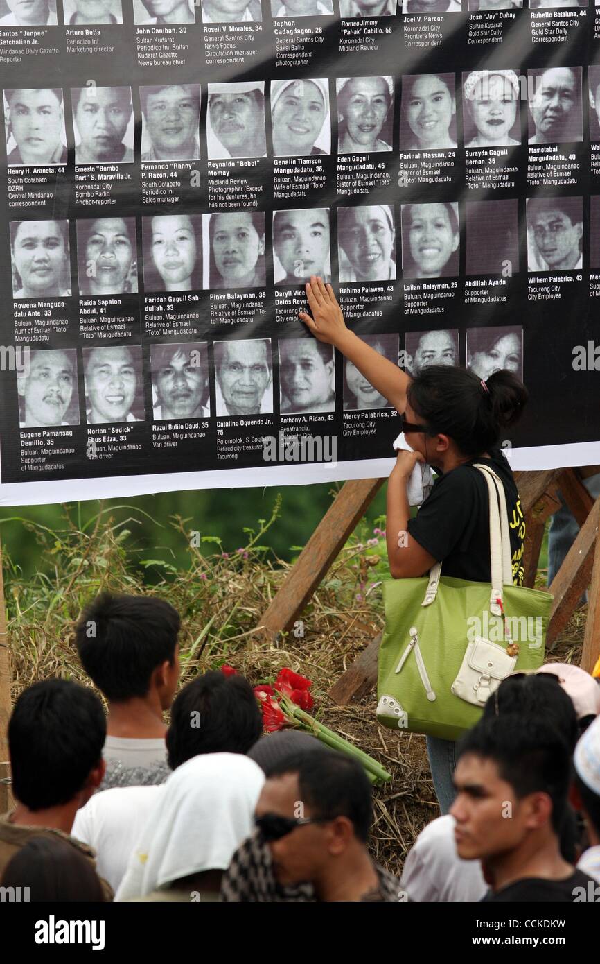 Novembre 23, 2010 - Maguindanao , Filippine - una relativa di uno dei 57 vittima nella peggiore della violenza politica nelle Filippine sud tocca il collage di immagini di vittime nella città di Ampatuan a Maguindanao dove 57 persone sono stati macellati dopo gli ordini di una sentenza clan musulmano. Filippine Foto Stock