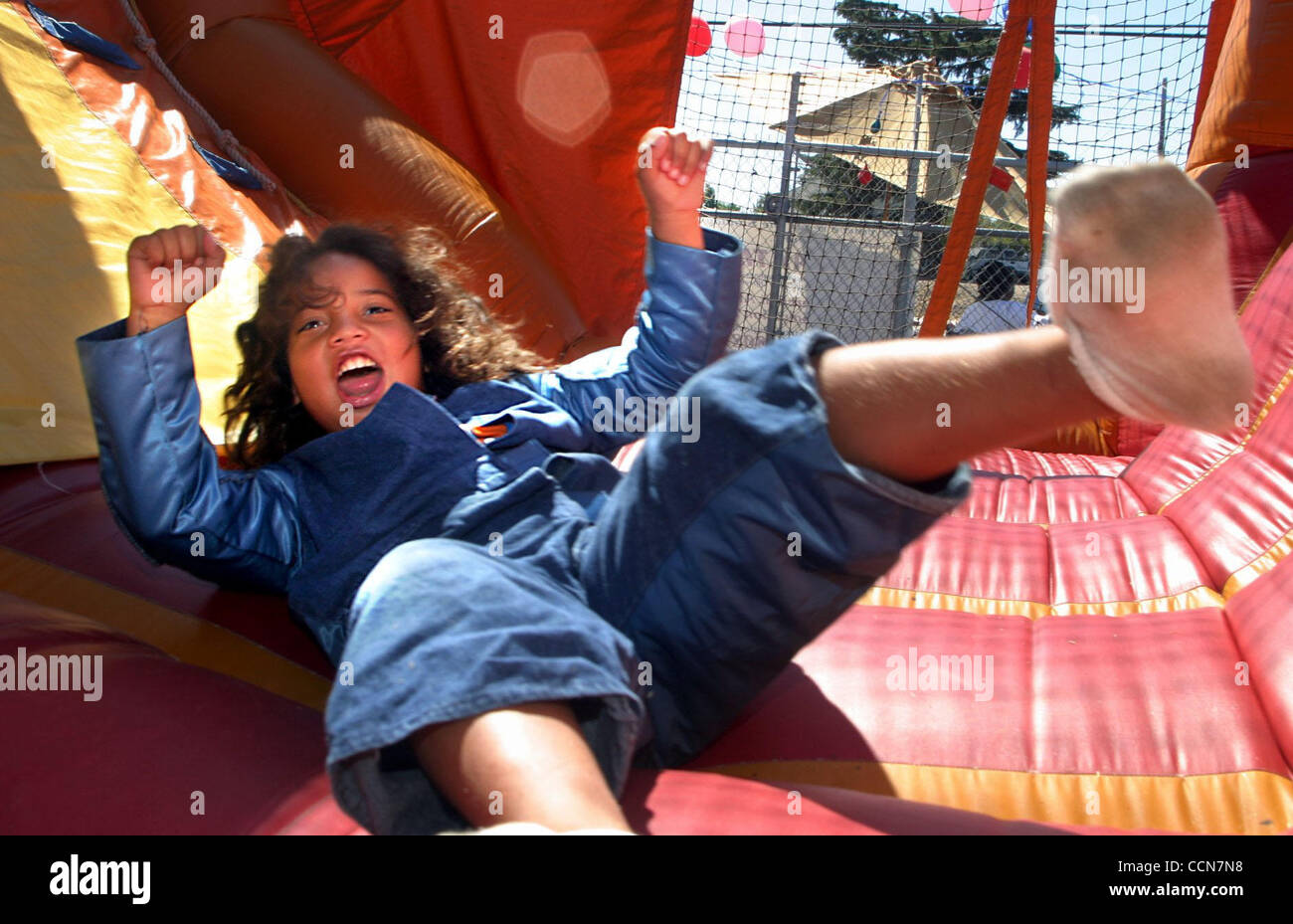 Adrian Orduno (CQ), dieci anni di Antiochia, solleva le braccia dopo essere arrivati a una fermata in una diapositiva gonfiato presso la Chiesa di Antiochia dell'Esercito della Salvezza's Kids Fun Festival Jamboree in Antiochia, California il sabato, 28 agosto 2004. (Dean Coppola/Contra Costa Times) Foto Stock