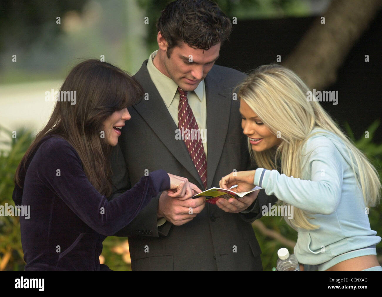 Jun 17, 2003; Los Angeles, CA, Stati Uniti d'America; la ex Joe Millionaire, EVAN MARRIOTT, recensioni un 'Filmaking for Dummies", libro con co-stars Amber Elias che gioca Miss Washington, sinistra e Gabrielle Tuite che gioca a Miss California sul set di "Miss Cast Away", il suo primo film. Foto Stock