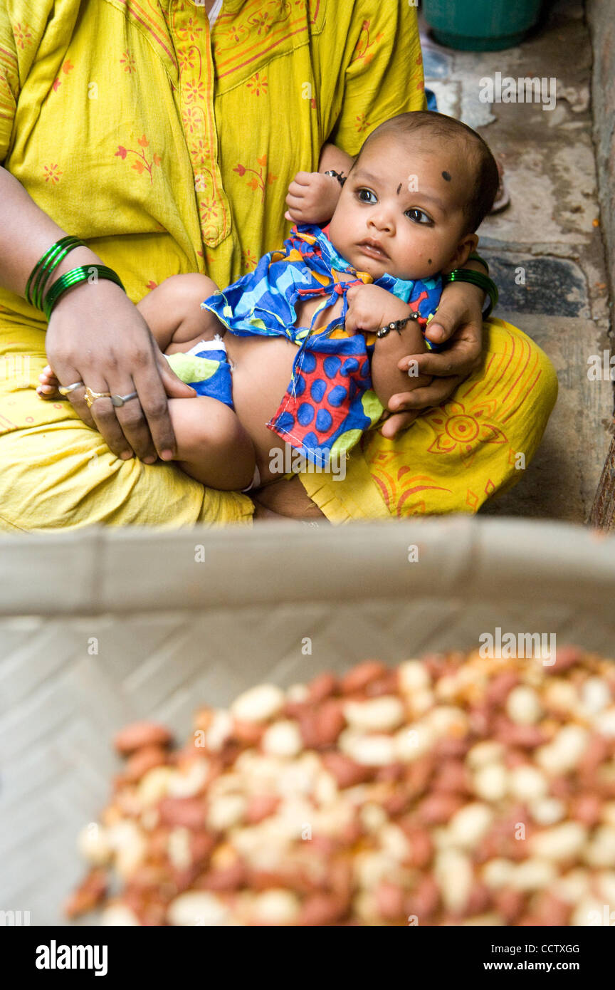 Aprile 30, 2010, Mumbai, India - Un giovane bambino siede sulla sua madre giro come lei e gli altri membri della famiglia ordina le arachidi in vendita dal loro domicilio nella Comunità Bainganwadi di Shivaji Nagar slum di Mumbai. (Credito Immagine: David Snyder/ZUMAPress) Foto Stock