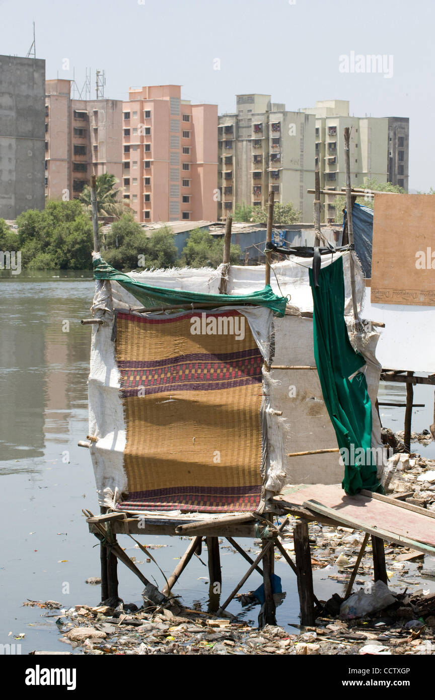 Aprile 27, 2010, Mumbai, India - Il fiume che scorre dal Shivaji Nagar slum di Mumbai, in India, è un tombino aperto portando malattia per le centinaia di migliaia di abitanti delle baraccopoli. Questa struttura è un wc, costruito sopra il fiume aperta, attraverso la quale è possibile vedere alto edificio di appartamenti di città che possono Foto Stock