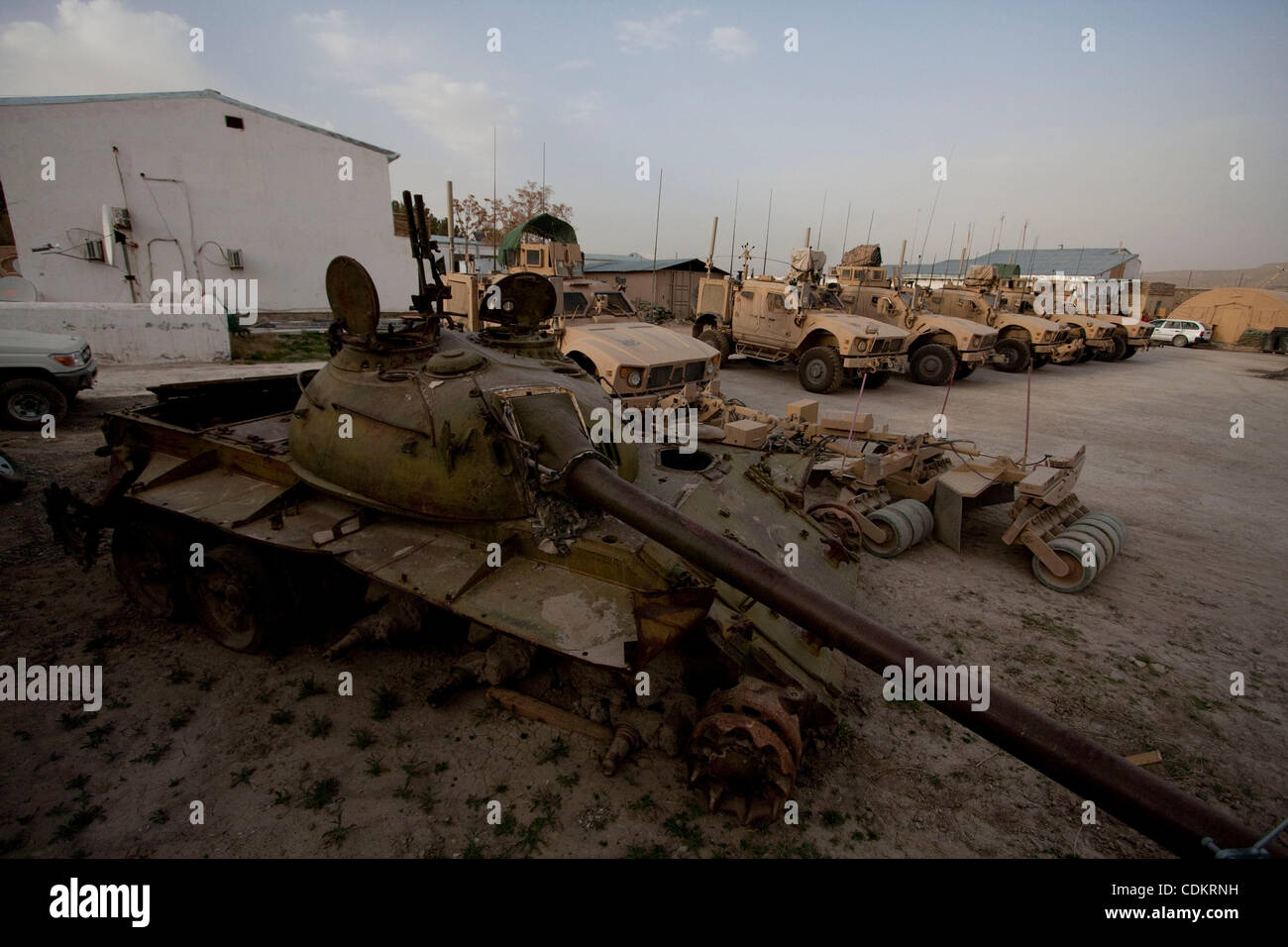 Mar 25, 2011 - Qalat, Provincia di Zabul, Afghanistan - un distrutto serbatoio sovietica riposa accanto a militari statunitensi MRAP (miniera resistente imboscata protetto) i veicoli a motore la piscina a inoltrare una base operativa (FOB) Smart nella capitale provinciale di Qalat nella provincia di Zabul. Con sede centrale a livello FOB Smart, il leader Foto Stock