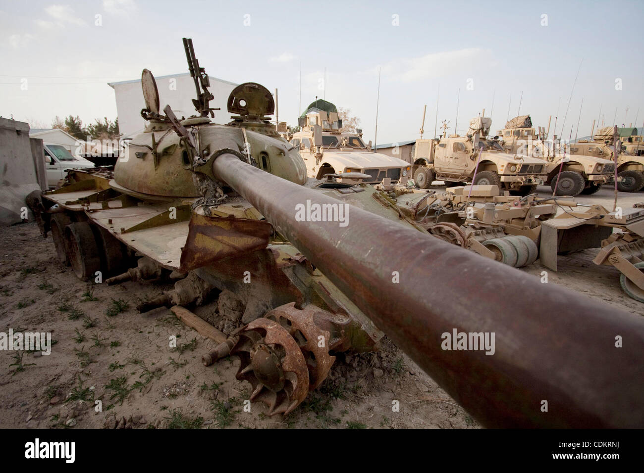 Mar 25, 2011 - Qalat, Provincia di Zabul, Afghanistan - un distrutto serbatoio sovietica riposa accanto a militari statunitensi MRAP (miniera resistente imboscata protetto) i veicoli a motore la piscina a inoltrare una base operativa (FOB) Smart nella capitale provinciale di Qalat nella provincia di Zabul. Con sede centrale a livello FOB Smart, il leader Foto Stock