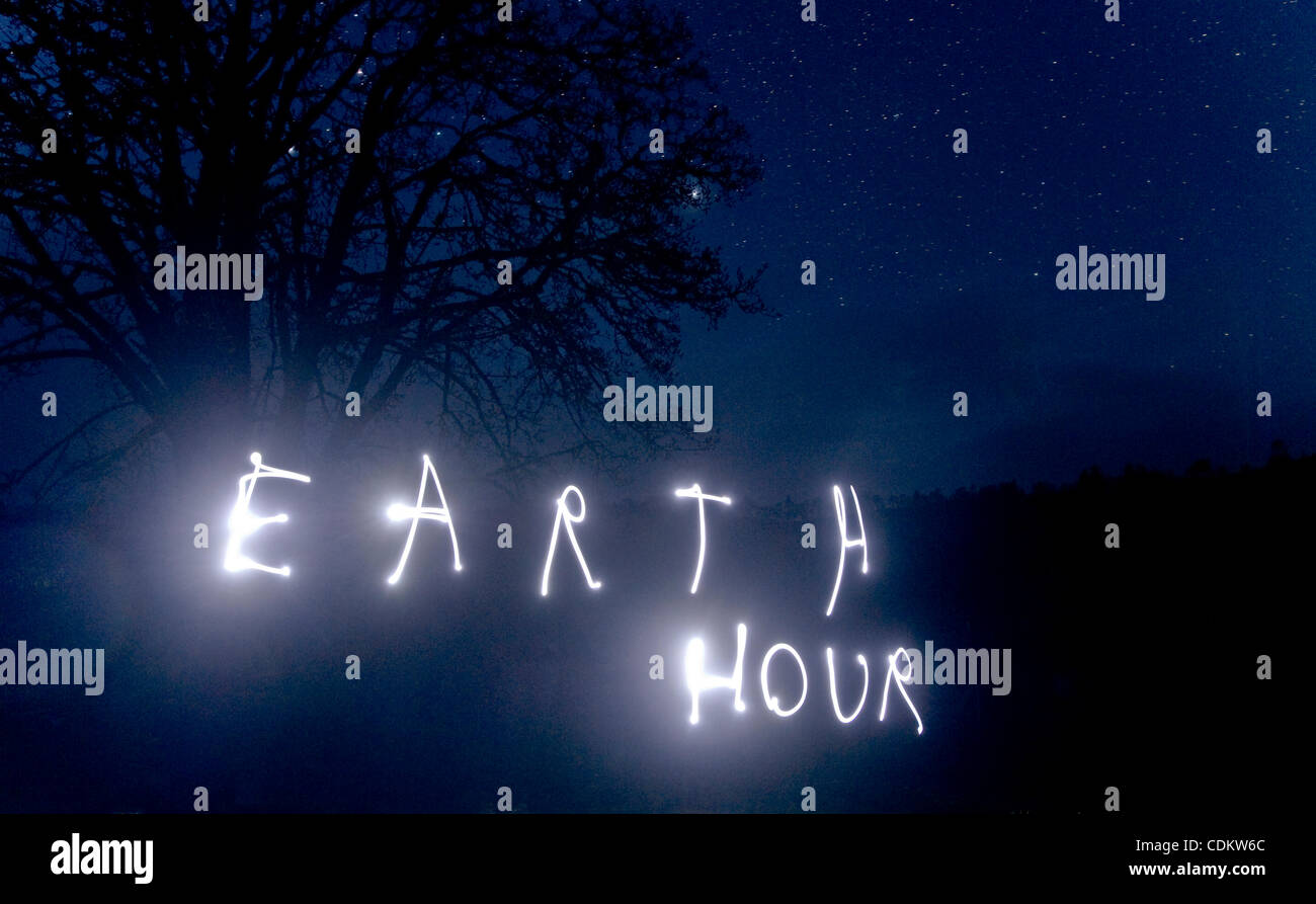 Mar 26, 2011 - Oakland, Oregon, Stati Uniti - un 14-anno-vecchio ragazzo utilizza una torcia elettrica per scrivere ''Earth Hour'' nel vialetto di casa sua nel rurale della contea di Douglas vicino a Oakland. Earth Hour è il più grande del mondo di movimento ambientale che incoraggia, individui, aziende e comunità per spegnere il loro paglierino Foto Stock