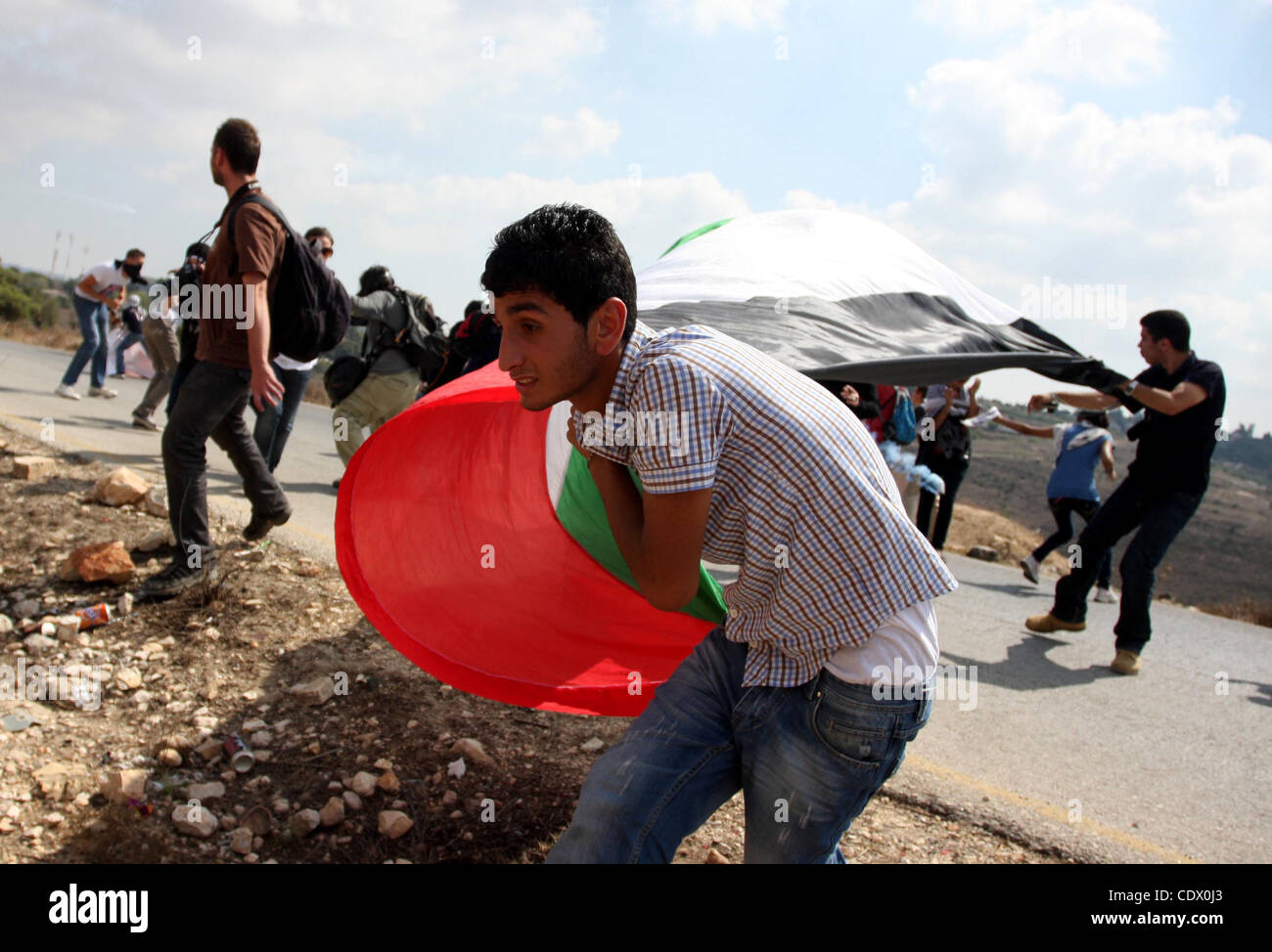 Giovani palestinesi wave la loro bandiera nazionale durante una manifestazione settimanale contro insediamento israeliano di espansione, in Cisgiordania villaggio di Nabi Saleh, il 7 ottobre 2011. Foto di Issam Rimawi Foto Stock