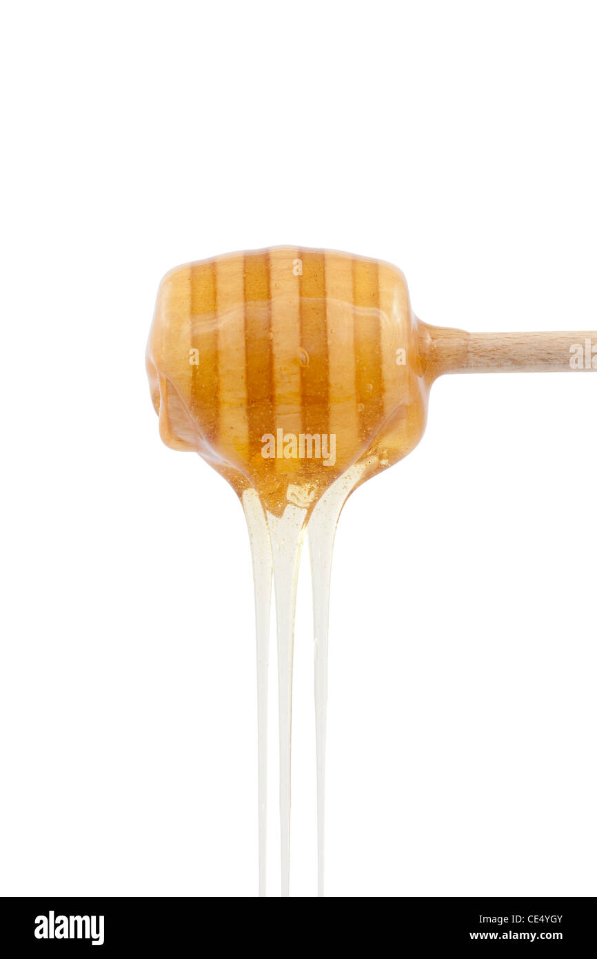 Il miele versando con il cucchiaio di legno su bianco Foto Stock