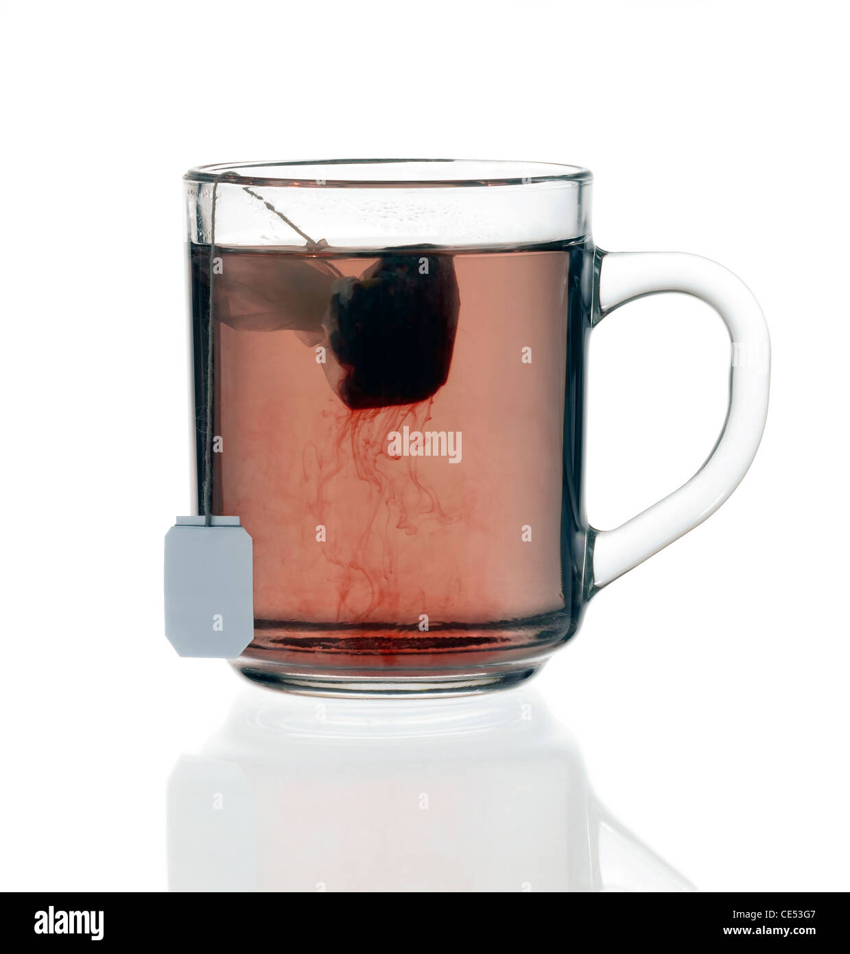 Vetro trasparente tazzina compresi liquido rossastro con un sacchetto da tè, sulla terra riflettente isolato su bianco con tracciato di ritaglio Foto Stock