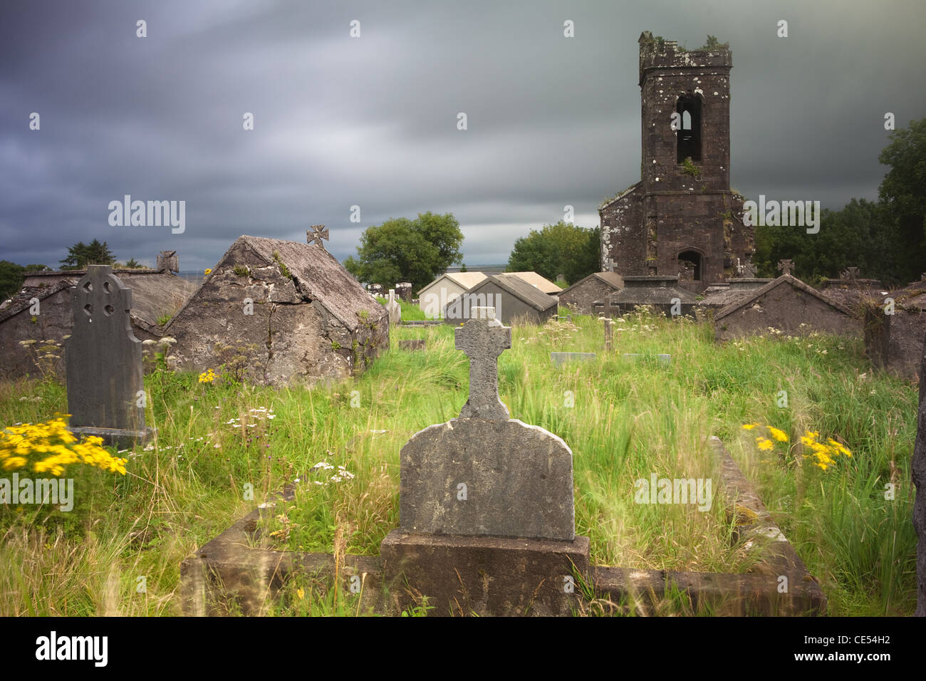 Irish cimitero alla penisola di Dingle vecchi ruderi della chiesa una lunga esposizione dà moody sentire causata dalla vegetazione sfocate e nuvole Foto Stock