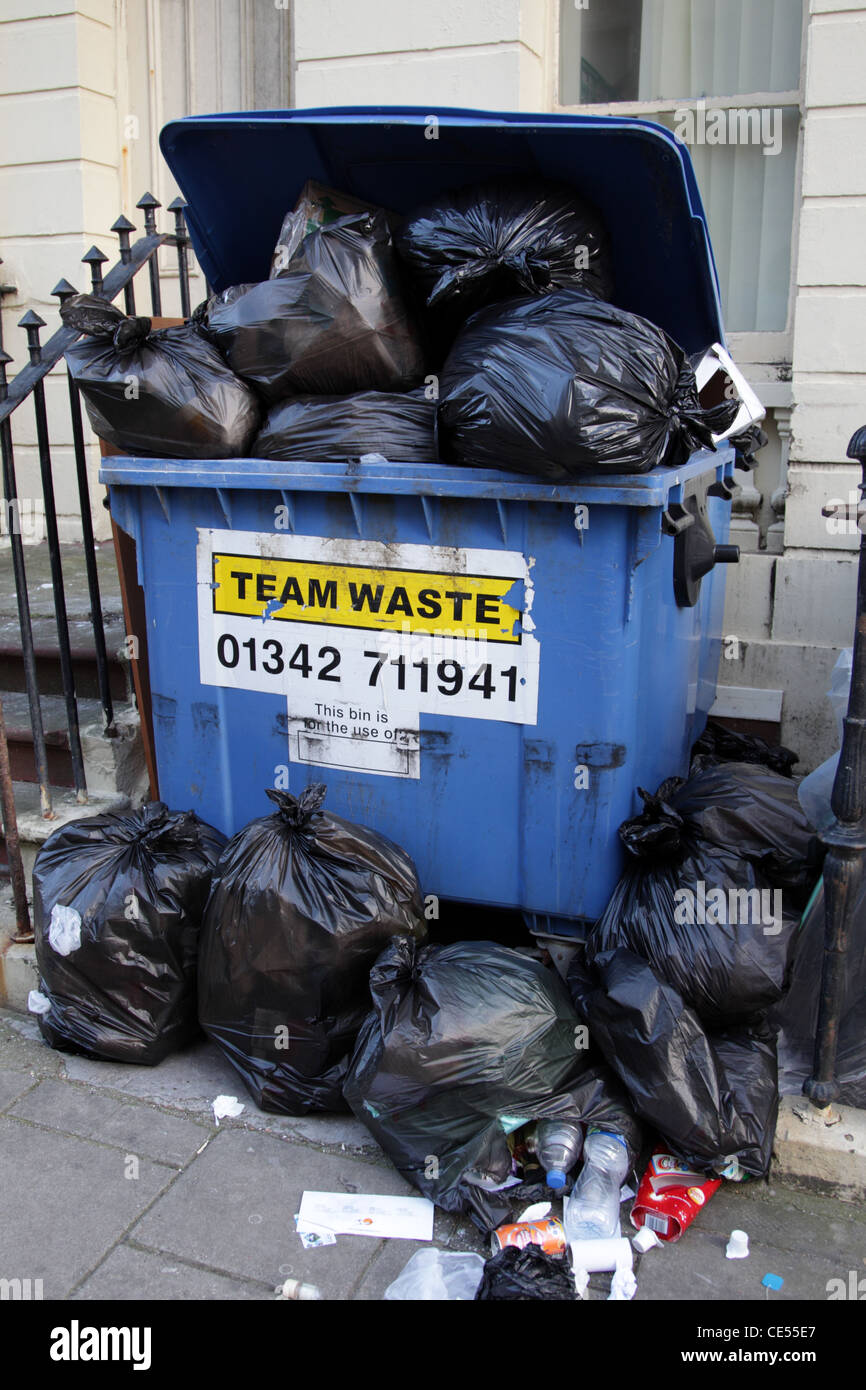 Un traboccante bidone dei rifiuti in una strada residenziale Brighton West Sussex England con sacchetti di burst riversandosi su strada Foto Stock