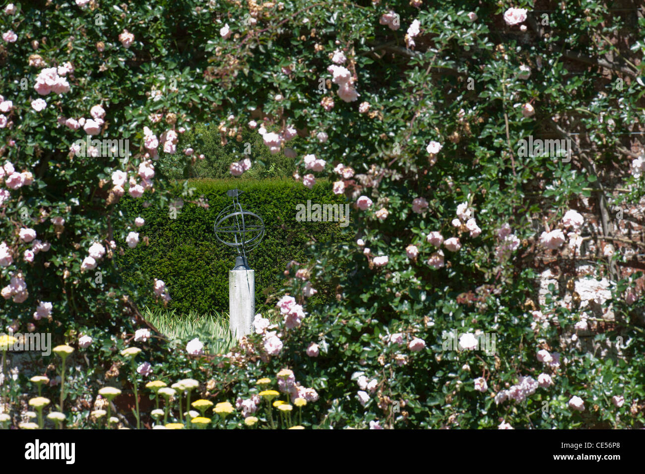 Vista di un giardino formale attraverso una 'finestra' in un vecchio muro, Surrey, Regno Unito Foto Stock