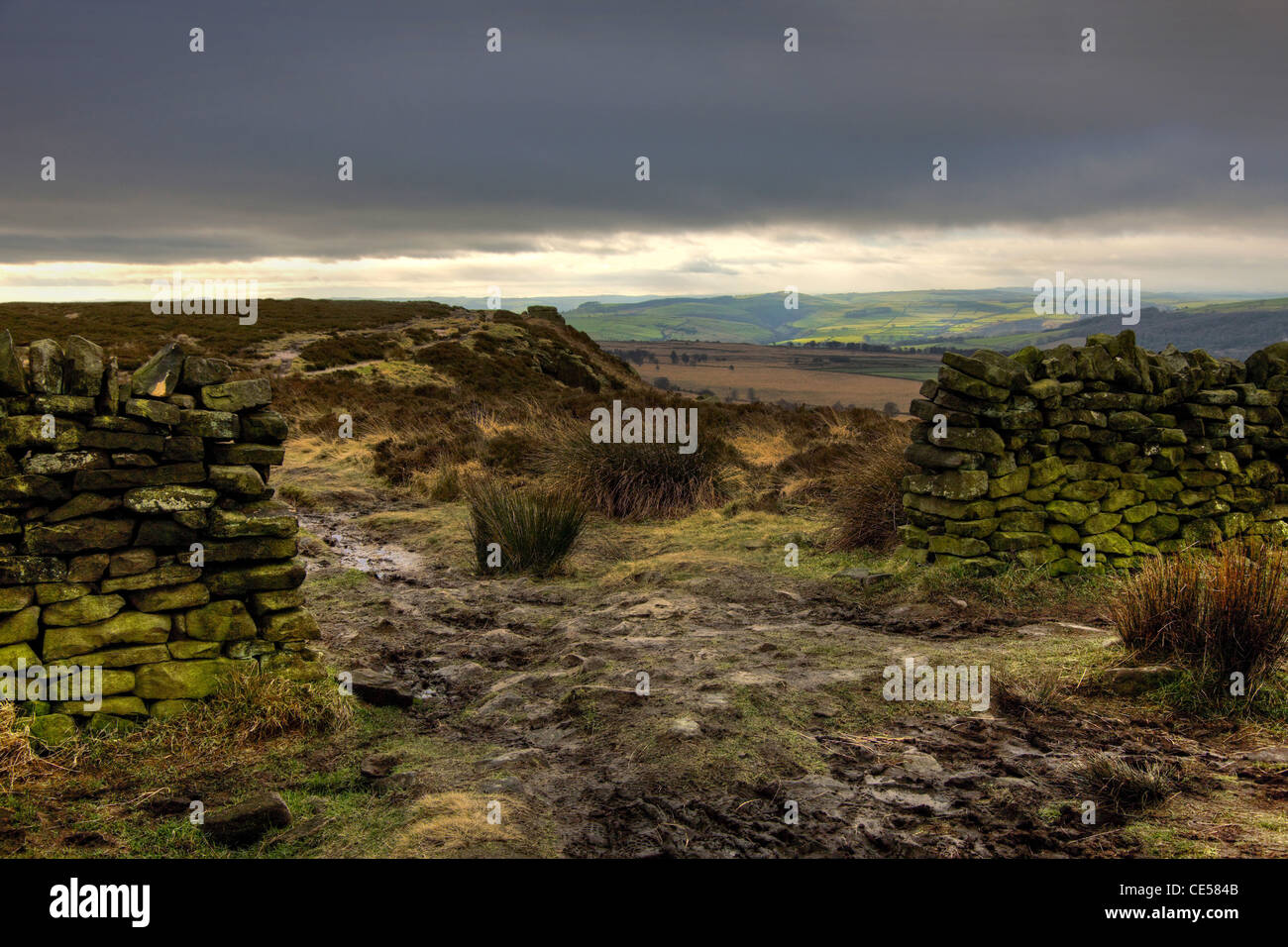 Percorso attraverso un gap in graniglia stalattite parete sul bordo bianco Moor vicino a Hathersage nel Derbyshire Peak District in inverno Foto Stock