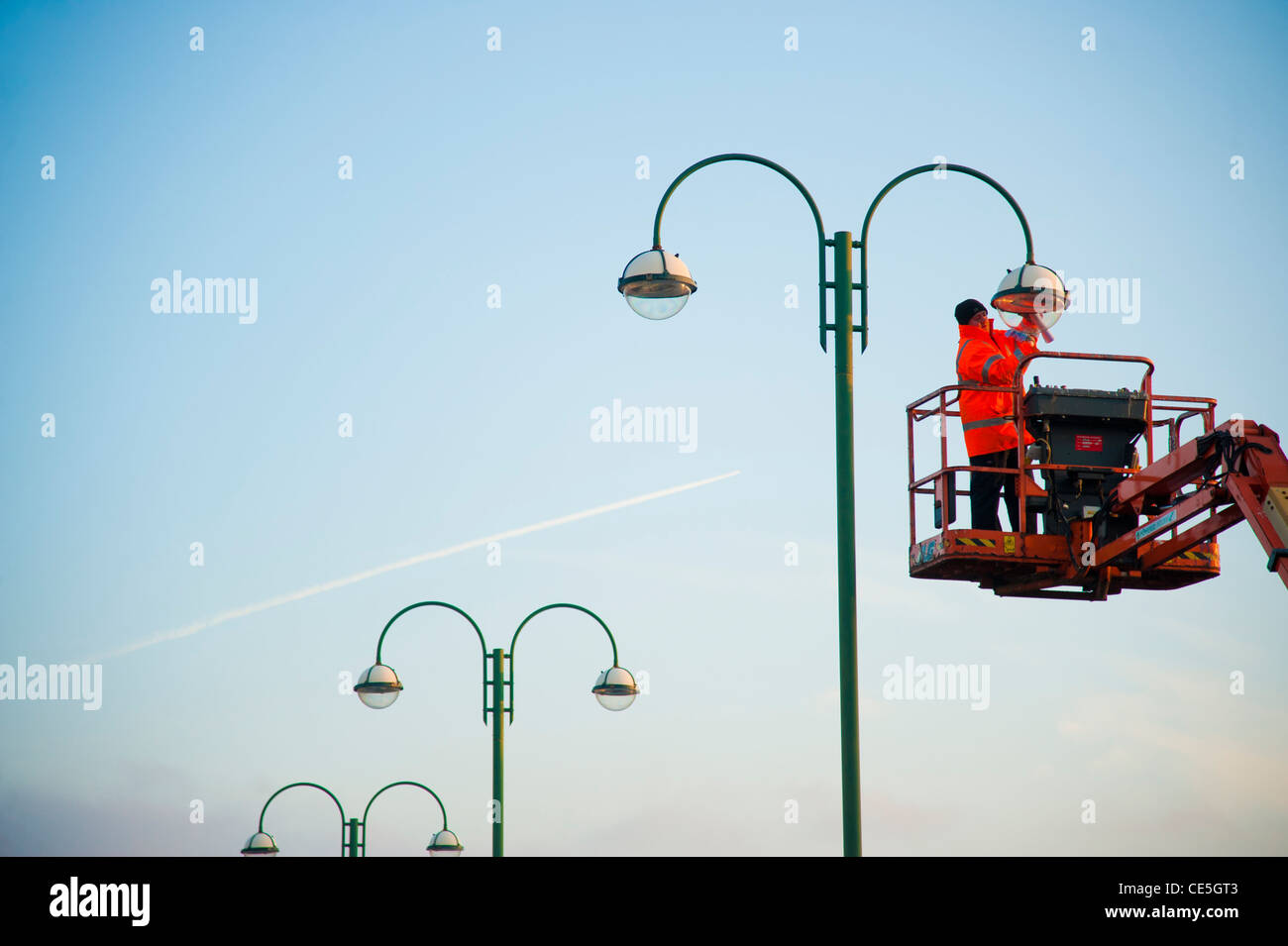 Un operaio lavora in altezza su una alta piattaforma di accesso mantenendo una strada lampada luce REGNO UNITO Foto Stock