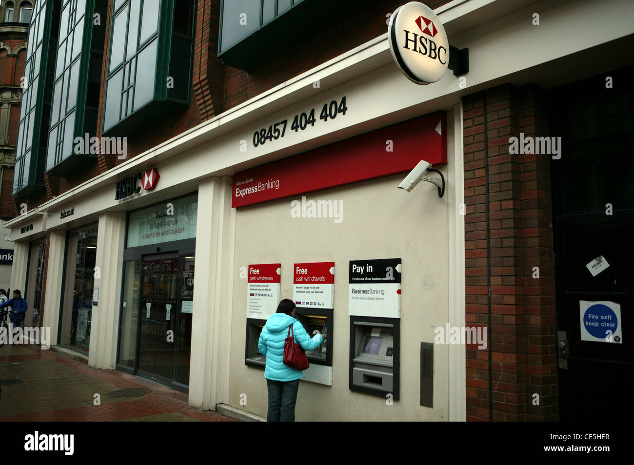 HSBC Bank Frontage, Royal Avenue rosso , Bianco & Nero logo, un Business Banking ATM, due normali ATM,.Persona presso ATM blue coat Foto Stock