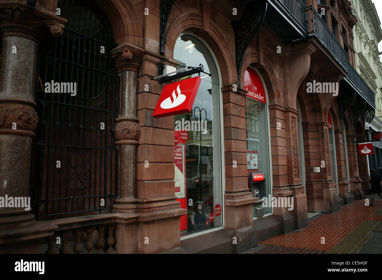Banca Santander, Royal Avenue rosso e il logo bianco, edificio in pietra arenaria, colonne scolpite. ATM , finestre ad arco. Cancelli di nero Foto Stock