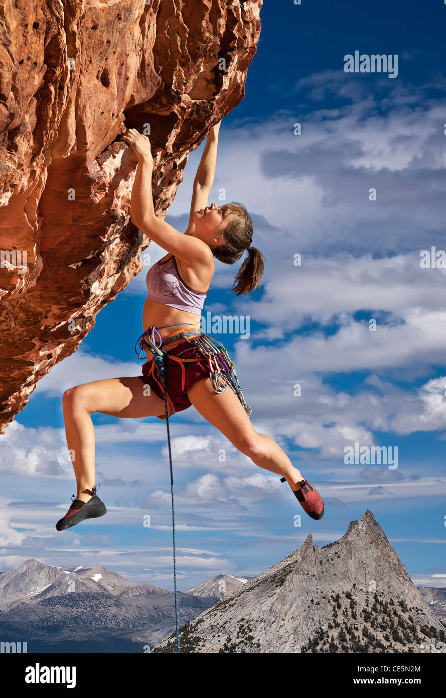 Femmina di rocciatore lotte per raggiungere il suo prossimo presa sul bordo di una scogliera impegnativo. Foto Stock