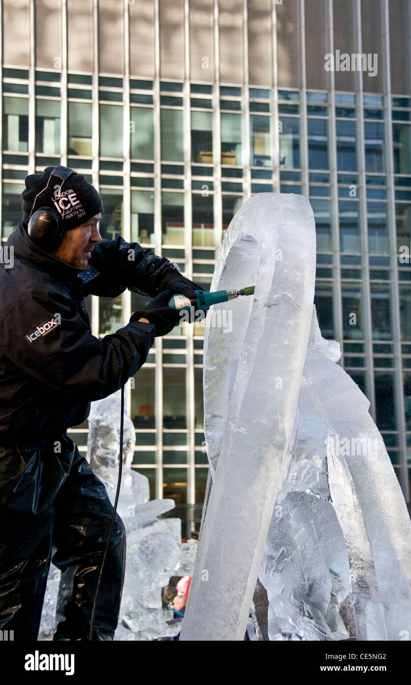 Scultore di ghiaccio al lavoro con uno scalpello Scultura su ghiaccio Festival Canary Wharf Londra Inghilterra Europa Foto Stock