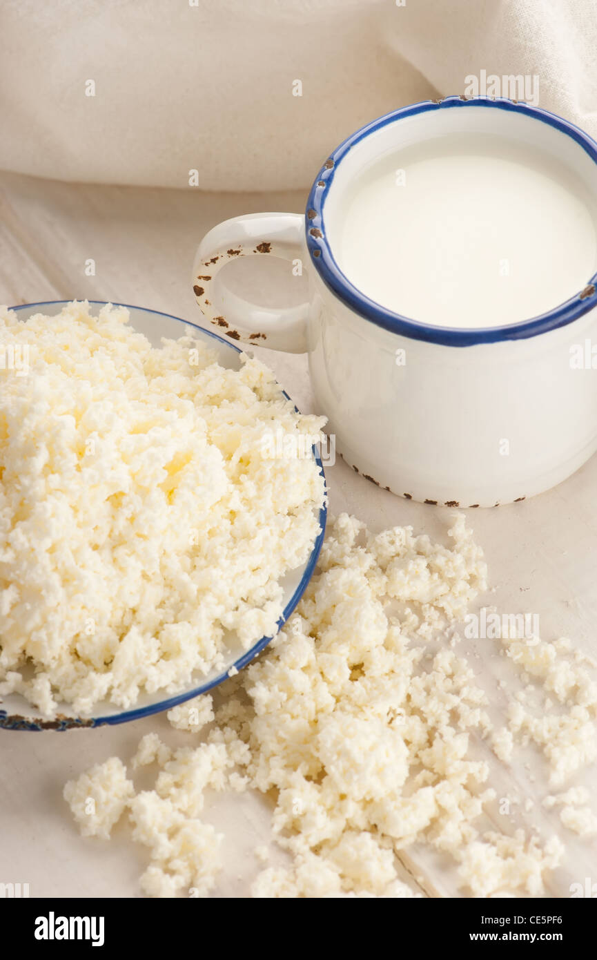 La prima colazione con il latte e il formaggio su un vecchio tavolo di legno con tovaglie di lino Foto Stock