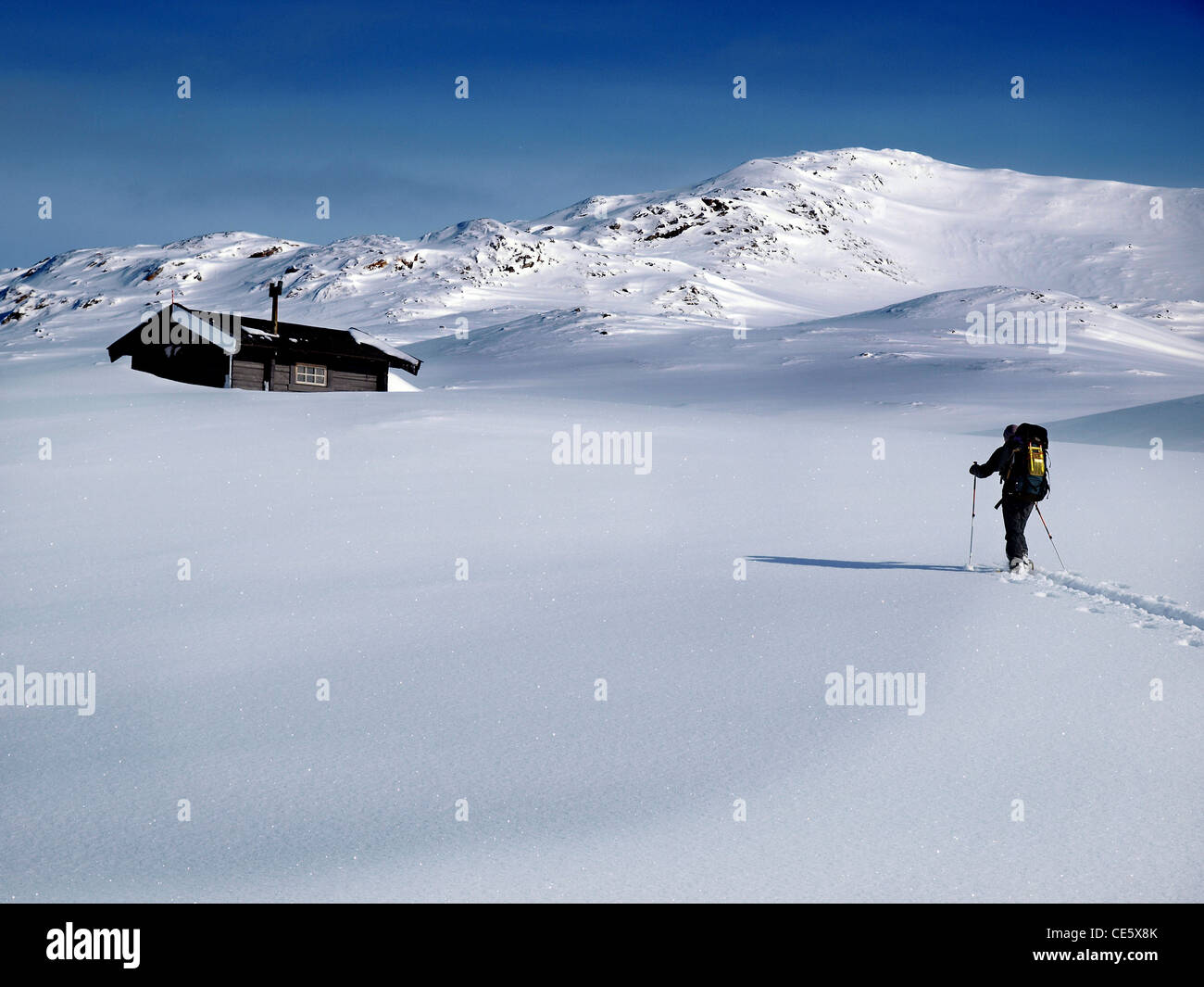 Una ski tourer avvicinando un Norvegese baita di montagna in inverno, Norvegia Foto Stock
