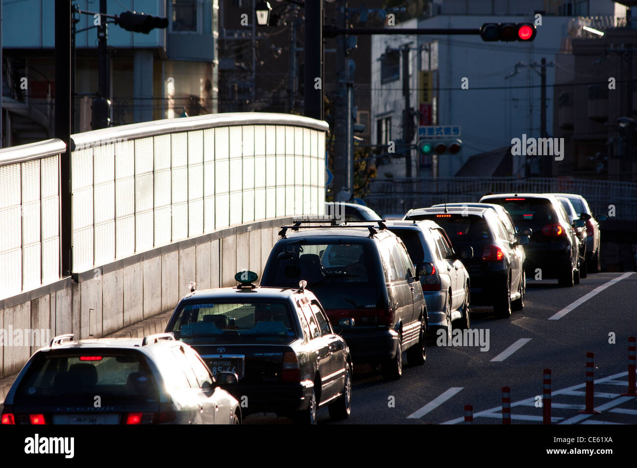 Vista ad alto contrasto lungo un'unica linea di auto in attesa di un semaforo rosso sulla strada Yamate Kansen a Shukugawa, Nishinomiya, Giappone. Foto Stock