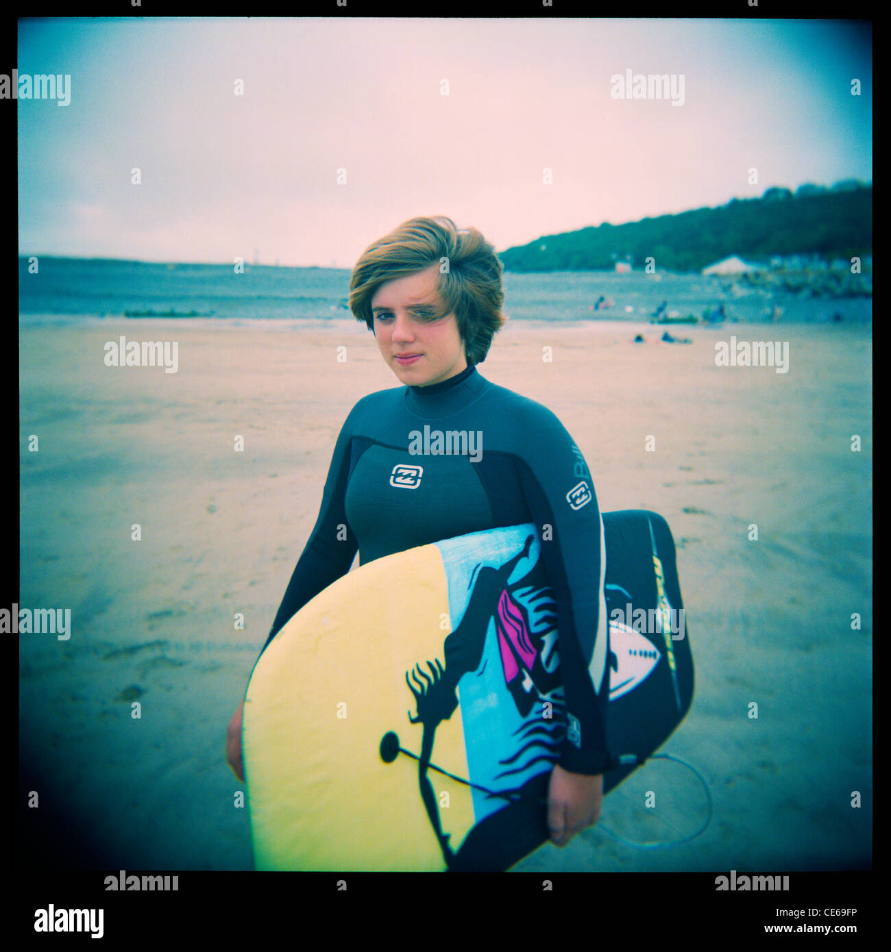 13 year old girl portante un corpo-board sulla spiaggia di Condino, Devon, Inghilterra. Prese con una Holga medio formato fotocamera giocattolo. Foto Stock