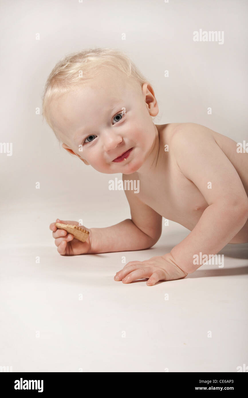 Biondo e bimbo neonato bambino europeo ritratto in studio con un cookie in mano Foto Stock