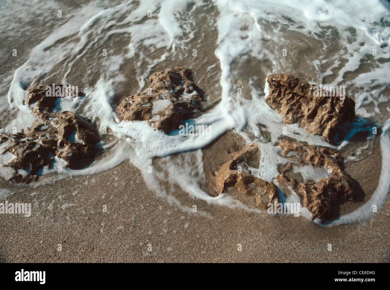 Acqua di mare surf schiuma di sabbia e scogli Foto Stock